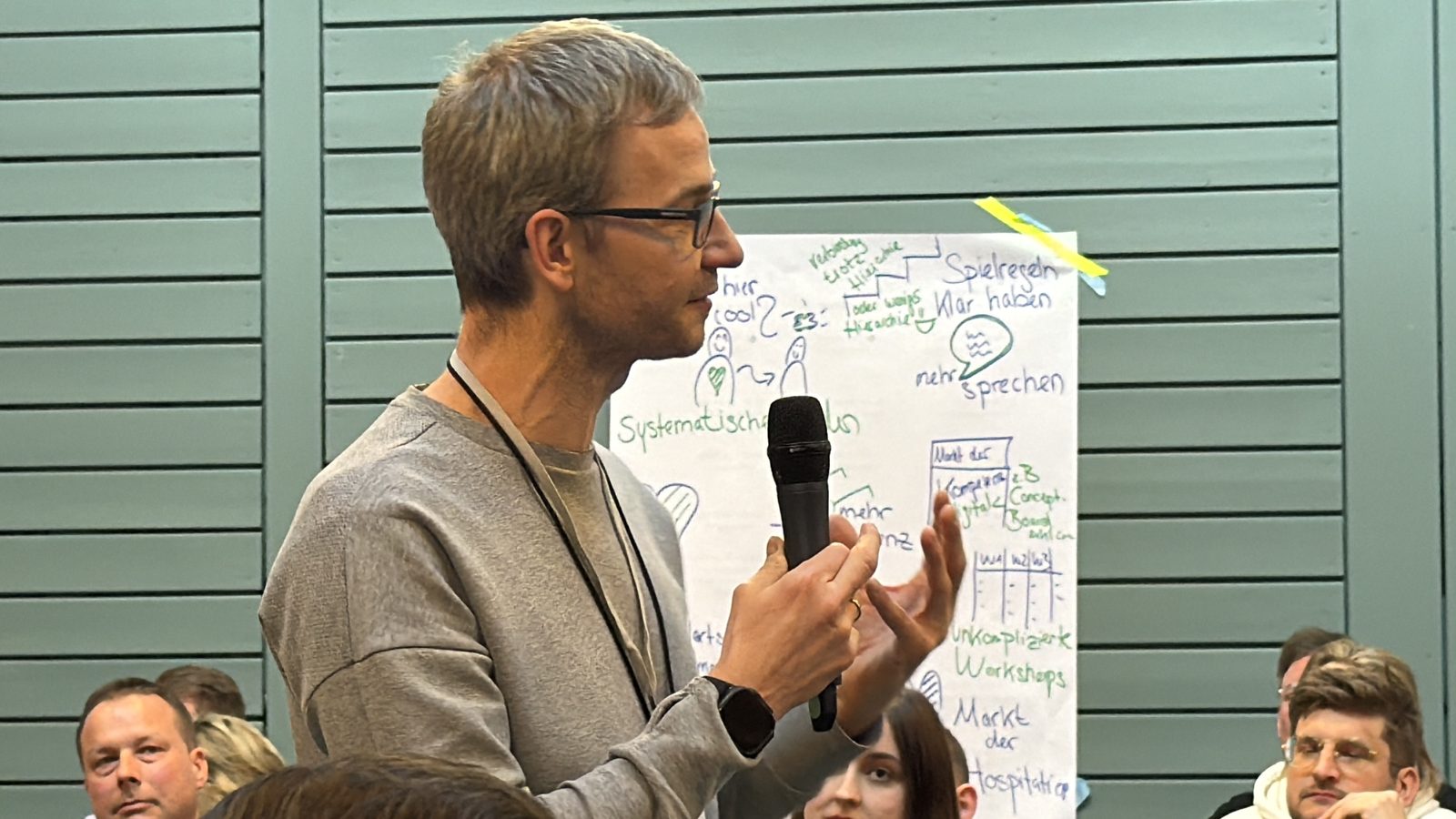 Wortmeldung vor einem Flipchart mit den Ergebnissen einer Werkstatt