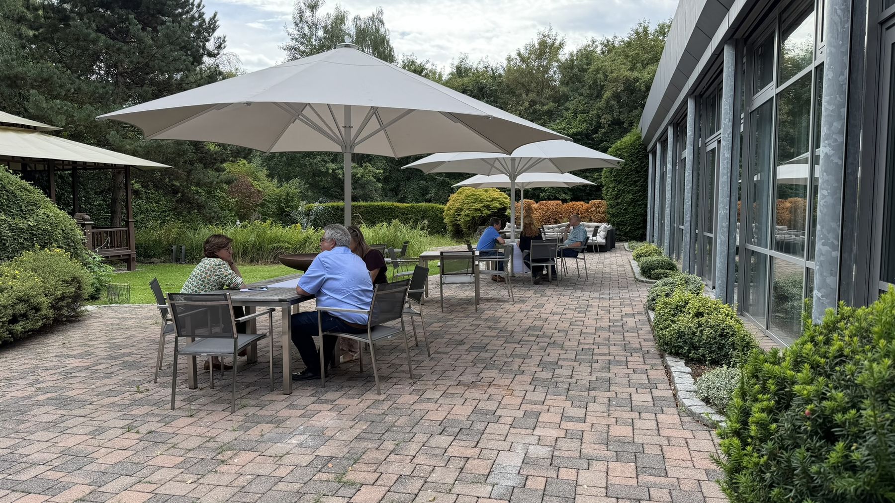 Arbeitsgruppen der Klausur an Tischen auf der Terrasse des Tagungsorts