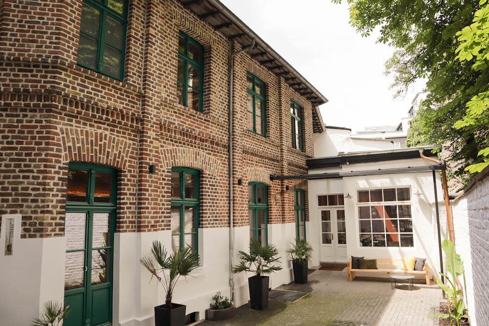 Privater Innenhof der Alten Buchbinderei mit Backsteinfassade und grünen Sprossenfenstern