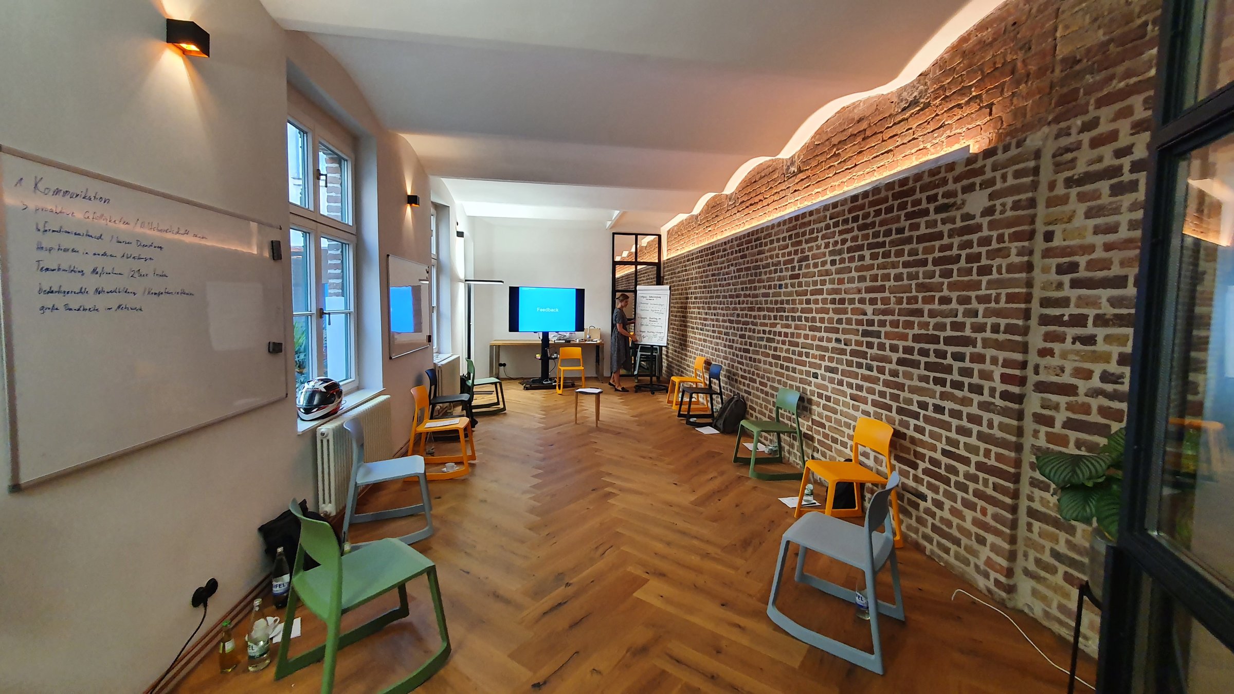 Seminarraum mit Stuhlkreis, Whiteboard und Backsteinwand
